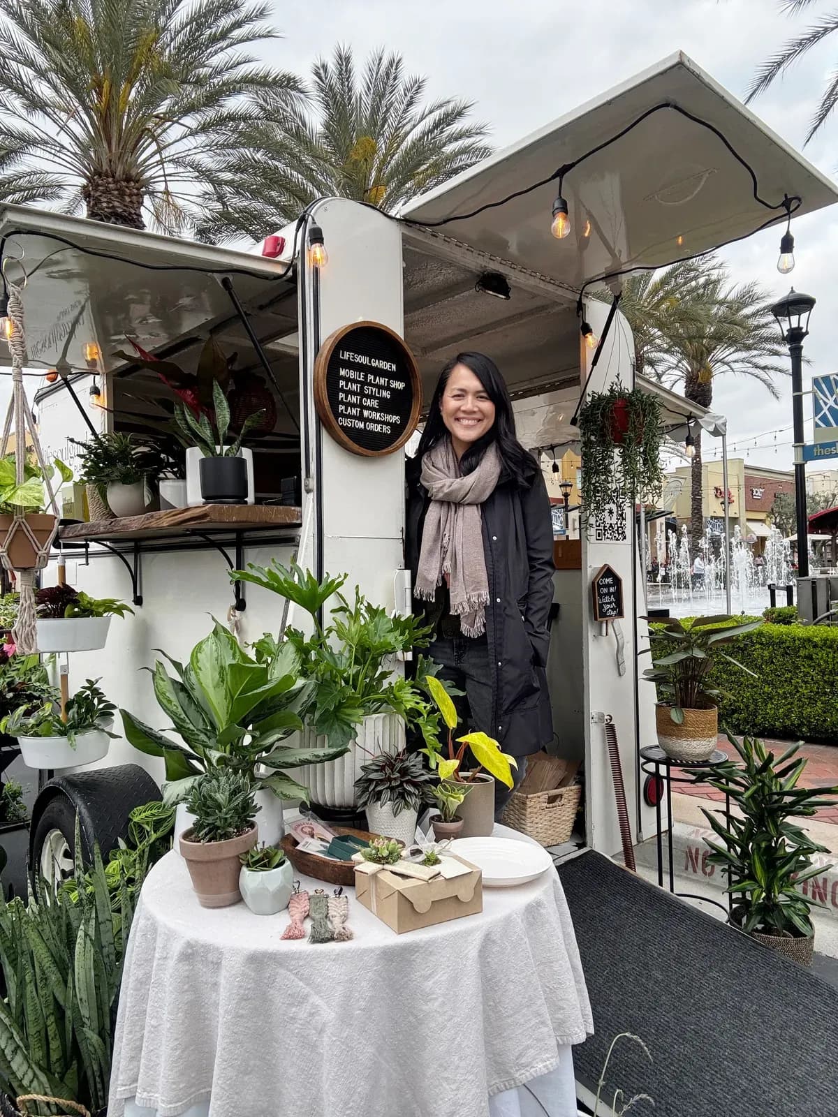 Nerissa smiling in the doorway of the lily pod, her mobile plant shop, surrounded by houseplants