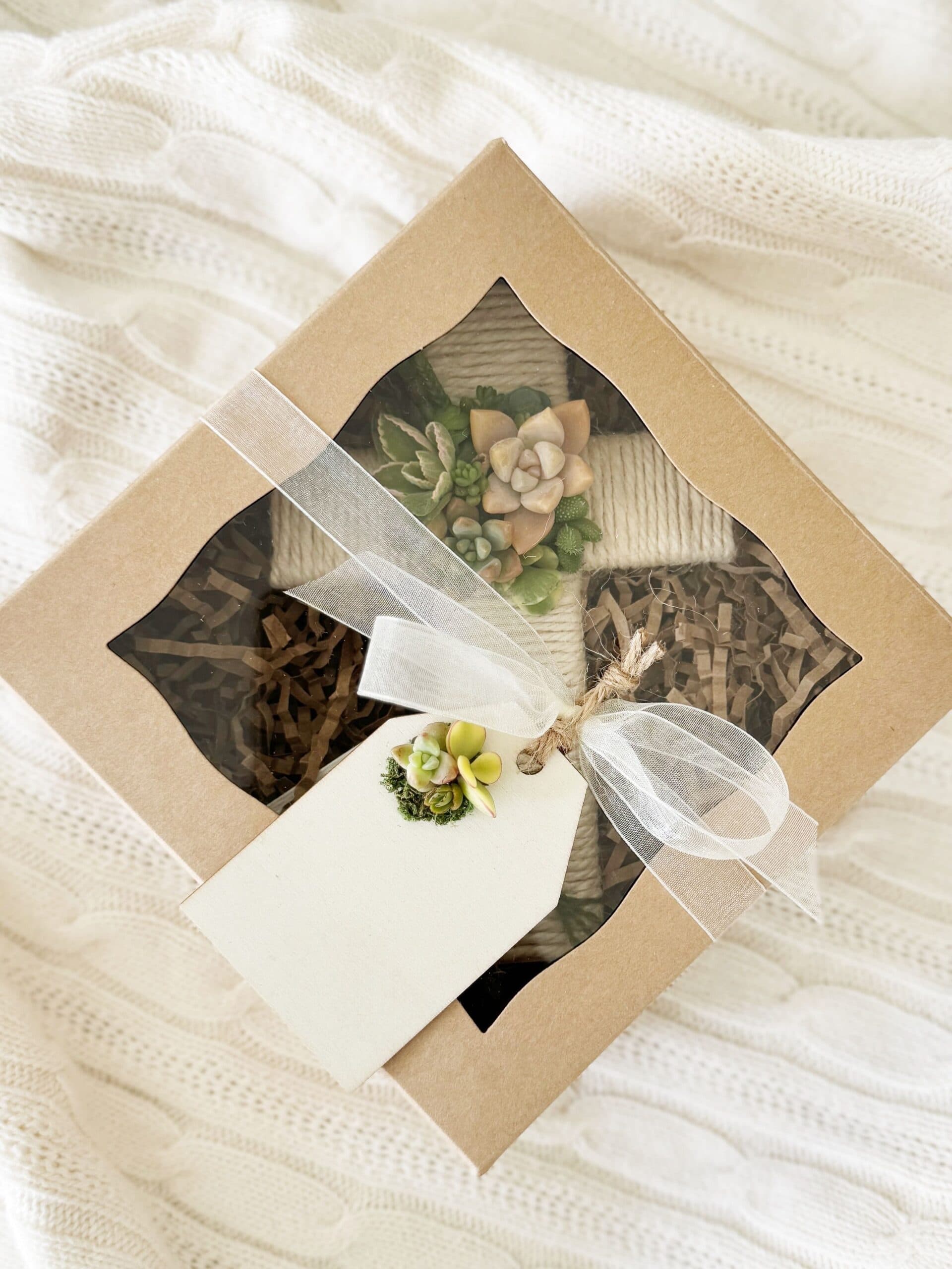 Succulent cross packaged in a windowed gift box with ribbon and tag