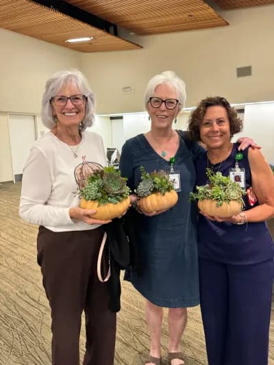 Three workshop guests holding the succulent bowls they made