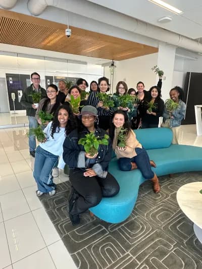 A team gathered on an office lounge sofa, each holding the plant they made