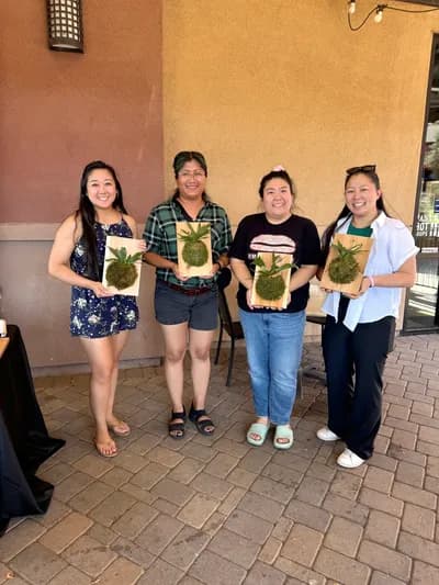 Four friends holding up the plants they potted at a private workshop