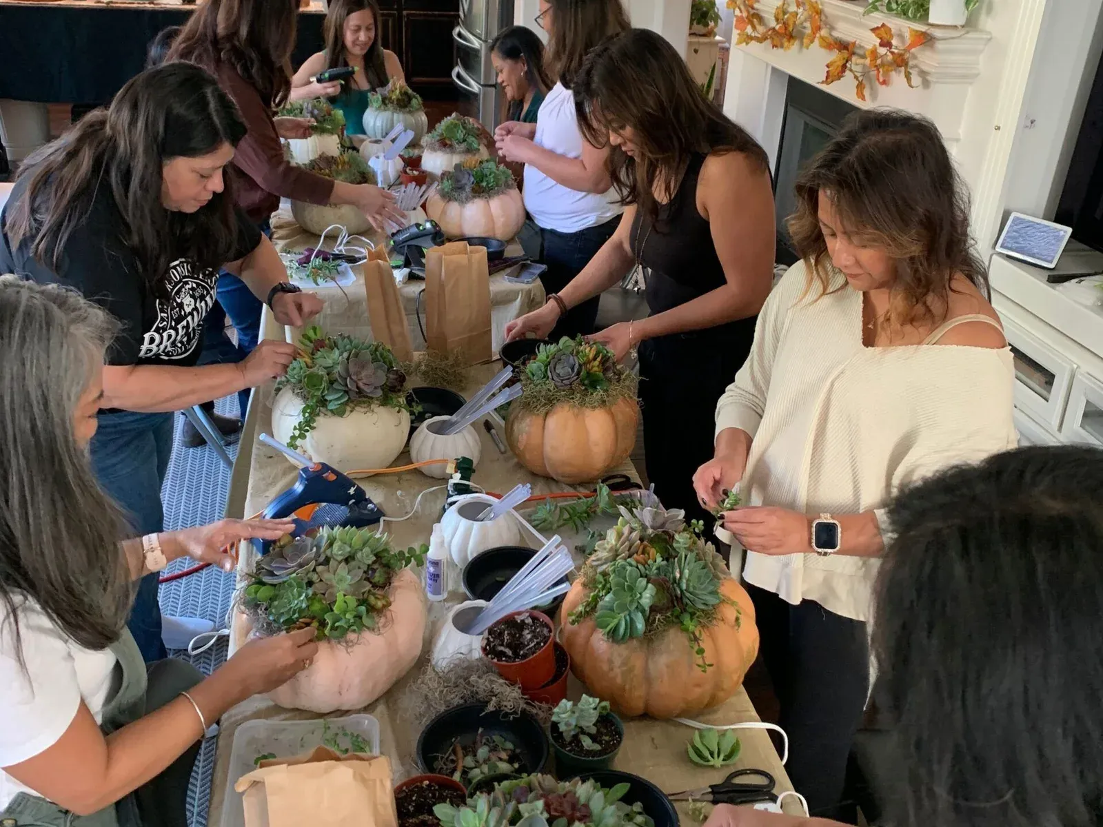 Friends planting succulents in pumpkins together at a private home workshop