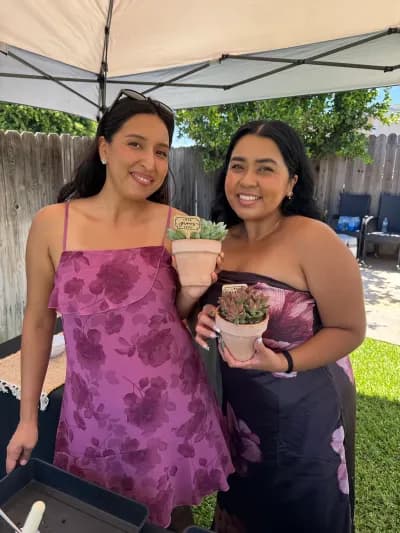 Two guests at a backyard party holding the plants they potted