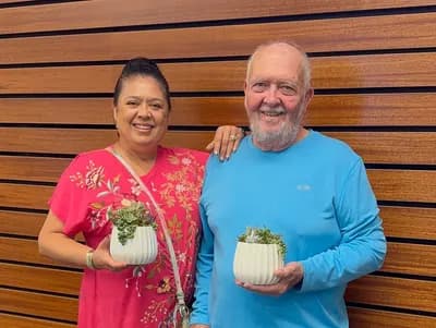 Two guests at a community workshop holding the succulent pots they planted