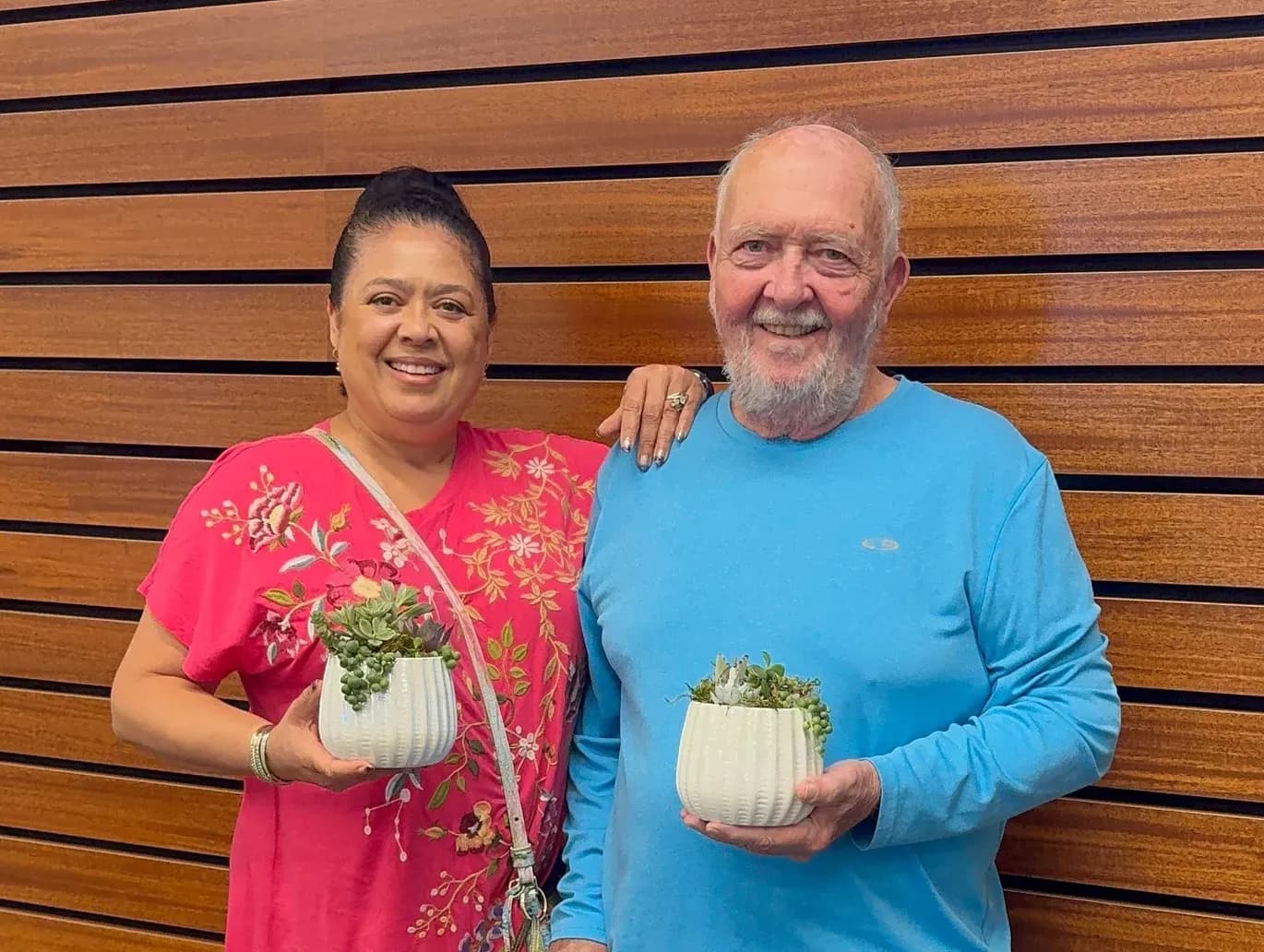 Two guests at a community workshop holding the succulent pots they planted