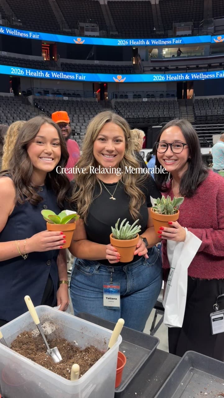 Three guests at a wellness fair holding the succulents they potted