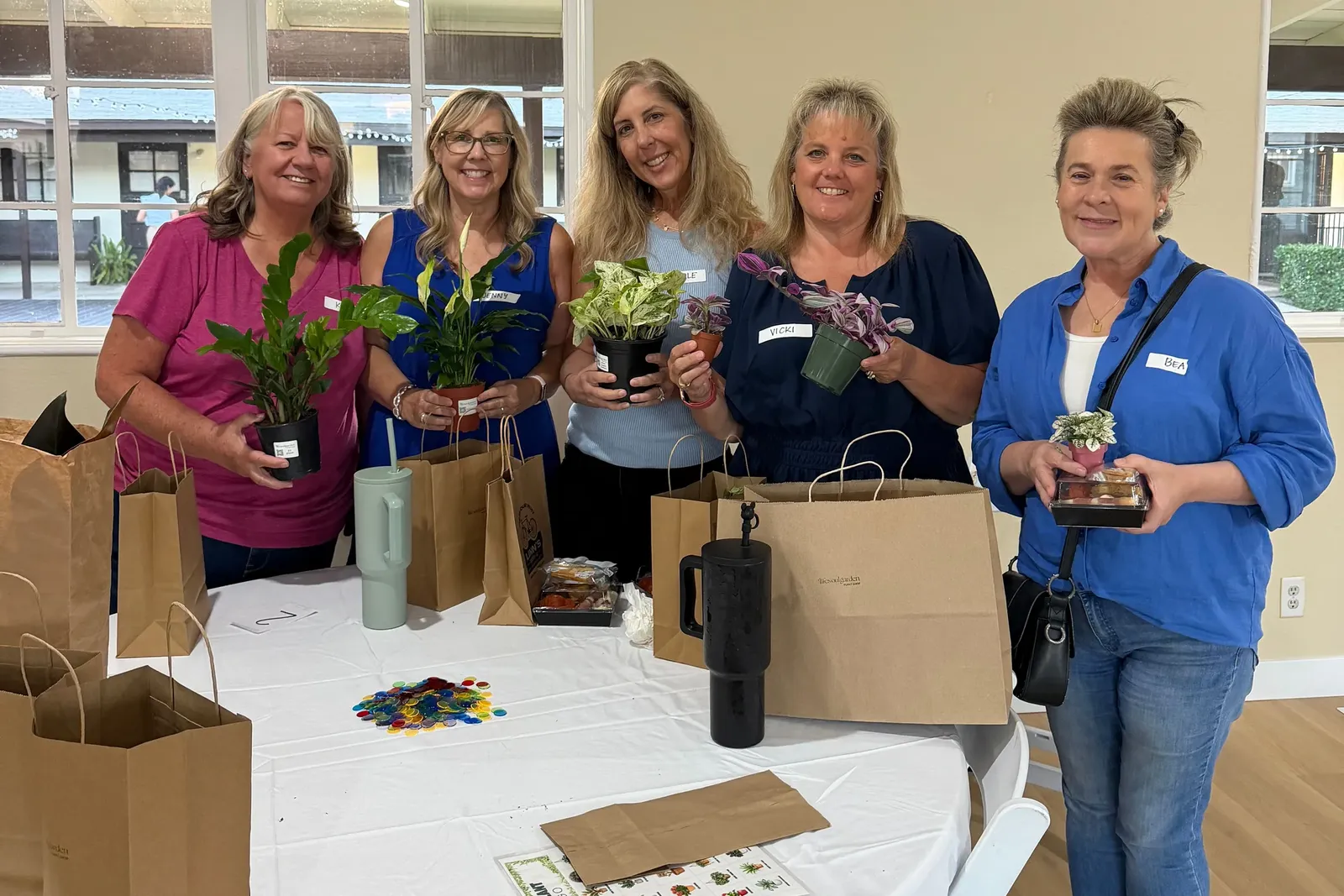 Five guests at a plant bingo night holding the houseplants they took home