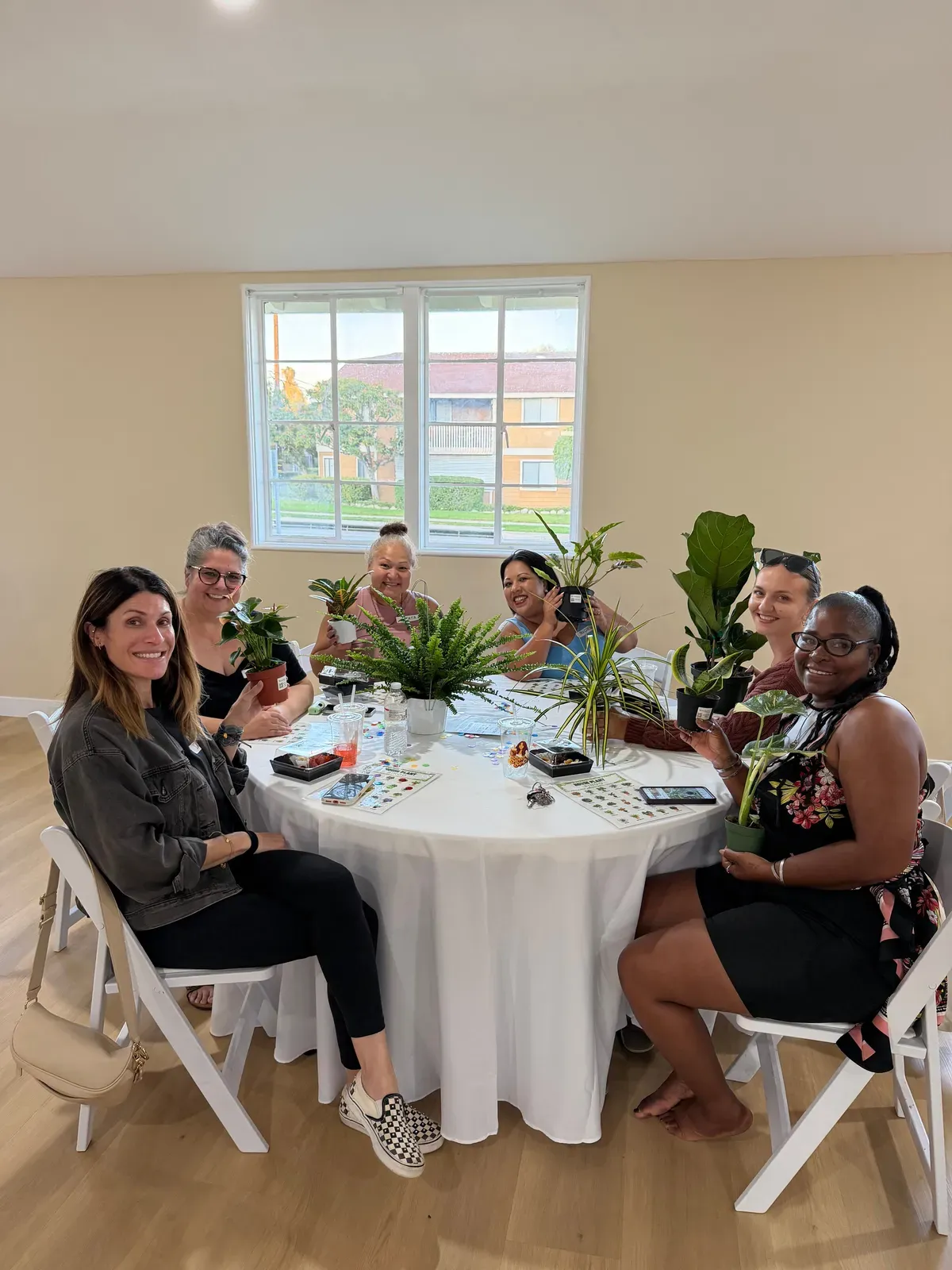Plant Bingo players around a table with their bingo cards and the potted plants they have won